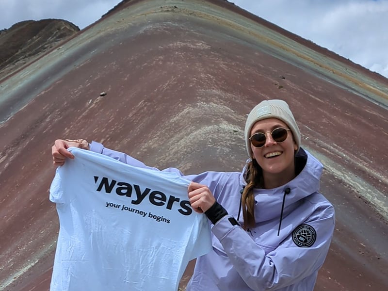 Frau mit weißem wayers Shirt vor den Rainbow Mountains in Peru